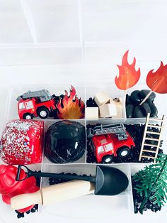 a plastic container filled with different types of toy trucks and firetrucks on top of a white table