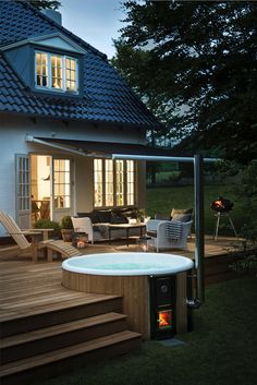 a hot tub sitting on top of a wooden deck next to a building with windows