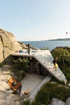 a child is standing on the roof of a house by the water's edge