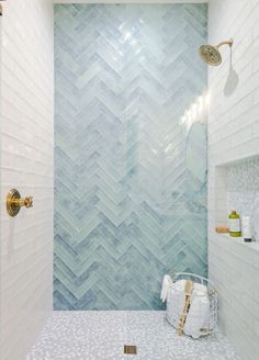 a bathroom with white and blue tiles on the wall, shower head, and tub