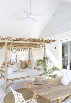 a white couch sitting on top of a wooden table next to a bed covered in pillows