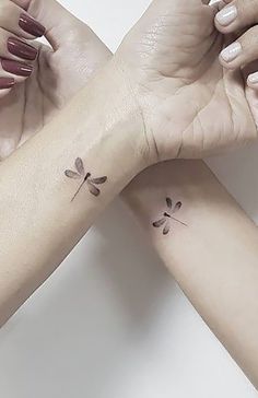 two women's wrist tattoos with dragonflies on them