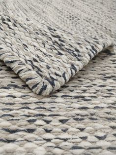 an area rug with black and white patterns on the bottom, in front of a gray background