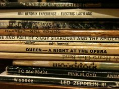 a stack of old records sitting on top of a wooden table next to a wall