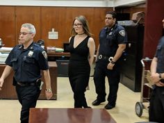 two police officers are walking in front of the judge's desk while three other people stand behind them