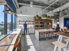 two men are standing in the middle of a large open kitchen with lots of counter space