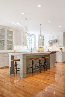 a large kitchen with white cabinets and wooden floors