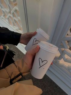 a person holding a coffee cup with two hearts drawn on it