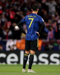 a soccer player is standing on the field with his hands on his hips looking down