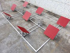 several red chairs sitting on top of a cement floor