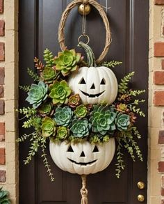 two pumpkins decorated with succulents and greenery are hanging on the front door