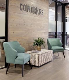 two chairs and a table in front of a wall with the words cowworkrs on it