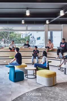 people are sitting in chairs and talking to each other at the front desk, while others sit on stools