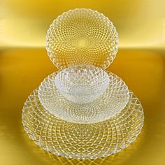 three glass plates stacked on top of each other in front of a yellow background,