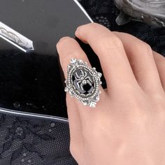 "Add some dark Gothic elegance to your outfit with this black gem and silver spider statement ring. 💀 DESCRIPTION: This novelty ring features a small spider charm that sits on top of a vintage jet black oval cabochon from Swarovski®. This large stone was hand set into a lace edge setting and then layered onto an ornate setting with flourishes and bead detailing. It was mounted onto an adjustable ring base with a simple band. 💀 SIZE: The vintage glass cabochon from Swarovski® measures 3/4 \" long by 1/2\" wide. This is a rare vintage item Article 2190/4. This stone was discontinued and is no longer produced by Swarovski®. The settings were made high quality sterling silver plated brass that was oxidized to give them a vintage feel. They were made and plated in the USA and are lead and nic