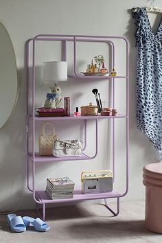 a pink shelf next to a toilet in a room with a mirror on the wall