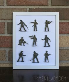 a shadow box with toy soldiers in it on a table next to a brick wall