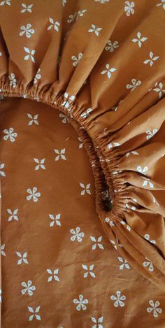 a brown and white flowered comforter with ruffles on the edges, sitting on a bed