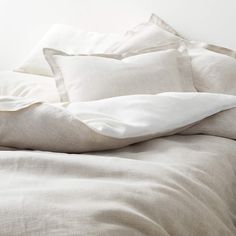 an unmade bed with white sheets and pillows