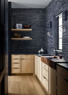 a kitchen with wooden cabinets and black wallpaper