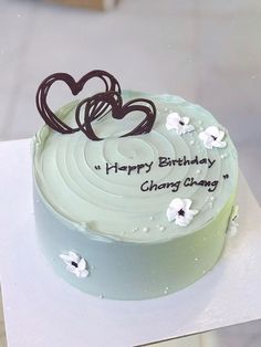 a birthday cake with white frosting and chocolate hearts on top that reads happy birthday, hong kong