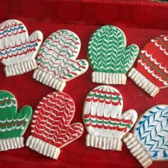 decorated cookies in the shape of mittens and gloves on a red tray, ready to be eaten