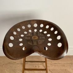 a wooden chair with holes in it on a hard wood floor next to a white wall