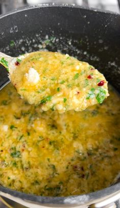 a ladle full of soup being stirred with a wooden spoon