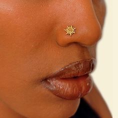 a woman's nose has a tiny sun piercing on it