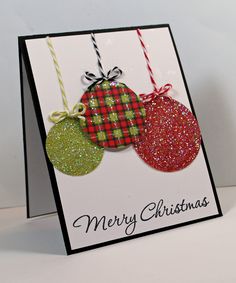 a christmas card with three ornaments hanging from it