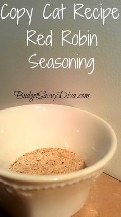 a white bowl filled with red robin seasoning on top of a wooden table next to a wall