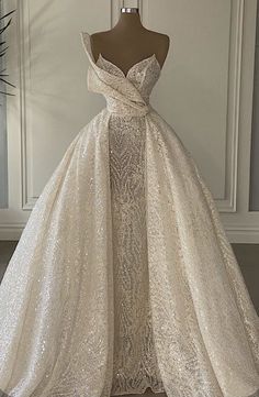 a wedding dress on display in front of a white wall