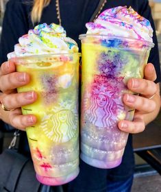 two people holding up colorful drinks in their hands