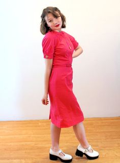 This is a very cute 1950s Bobbie Brooks cotton dress! It's a bright rose-raspberry pink color, in smooth soft cotton with a cute decorative front faux button placket that sports a large white moonglow Lucite button. Two matching buttons open and close at the short sleeve arm openings. The dress is demure with a Peter Pan collar, a trim waist seam with dyed to match string belt loops and a self fabric belt. The dress is shaped with vertical pleats, especially in the upper back where 2.5 inch spac 1950s Style Pink Dress For Vintage Fashion, 1950s Pink Vintage Dress, 1950s Style Pink Vintage Dress, Pink 1950s Vintage Fashion Dress, Pink 1950s Vintage Dress, Pink 1950s Vintage Style Dress, 1950s Pink Vintage Dress With Short Sleeves, 1950s Pink Vintage Summer Dress, 1950s Style Pink Daywear Dresses