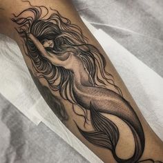 a woman's arm with a mermaid tattoo on it