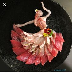 a woman in a dress made out of meat and vegetables on a black plate with white background