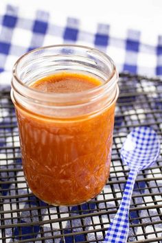 a jar filled with sauce sitting on top of a blue and white checkered table cloth