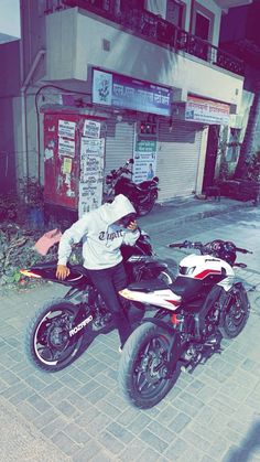 a man riding on the back of a motorcycle down a street next to a building