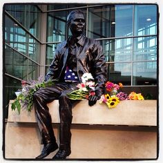 a man sitting on top of a window sill with flowers in front of him