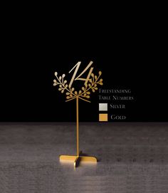 a gold table number stands on top of a black surface with the number four in it's center