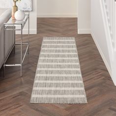 a white and gray striped rug on the floor next to a stair case in a living room