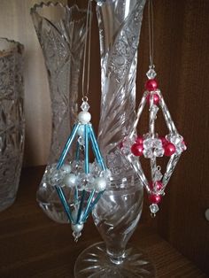 three glass ornaments sitting on top of a table next to vases and candlesticks