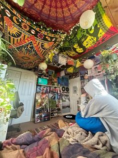 a woman sitting on top of a bed under a colorful canopy covered in lights and decorations