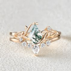 a green and white diamond ring sitting on top of a white surface with diamonds around it