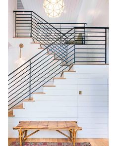 a wooden bench sitting under a stair case