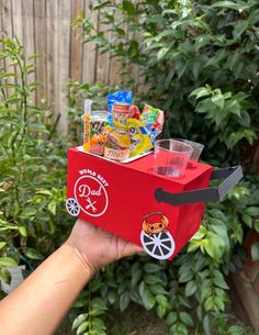 a person holding up a red box filled with candy