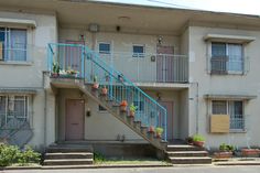 an apartment building with stairs leading up to the front door and flowers on the balconies