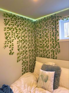 there is a bed with white sheets and green plants on the wall