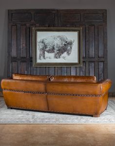 a leather couch in front of a framed bison print