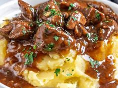 a white plate topped with mashed potatoes covered in meat and gravy